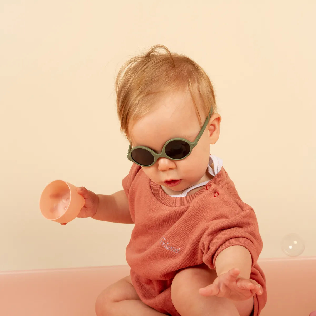 bébé jouant et portant lunette soleil kaki