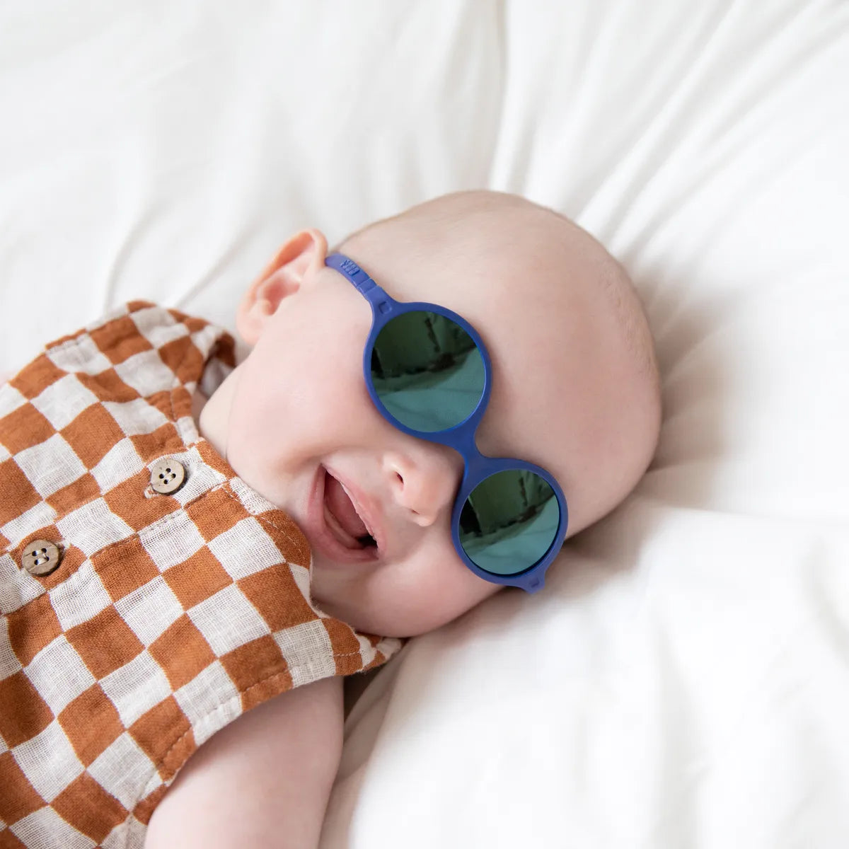 bébé souriant portant lunette soleil bleu