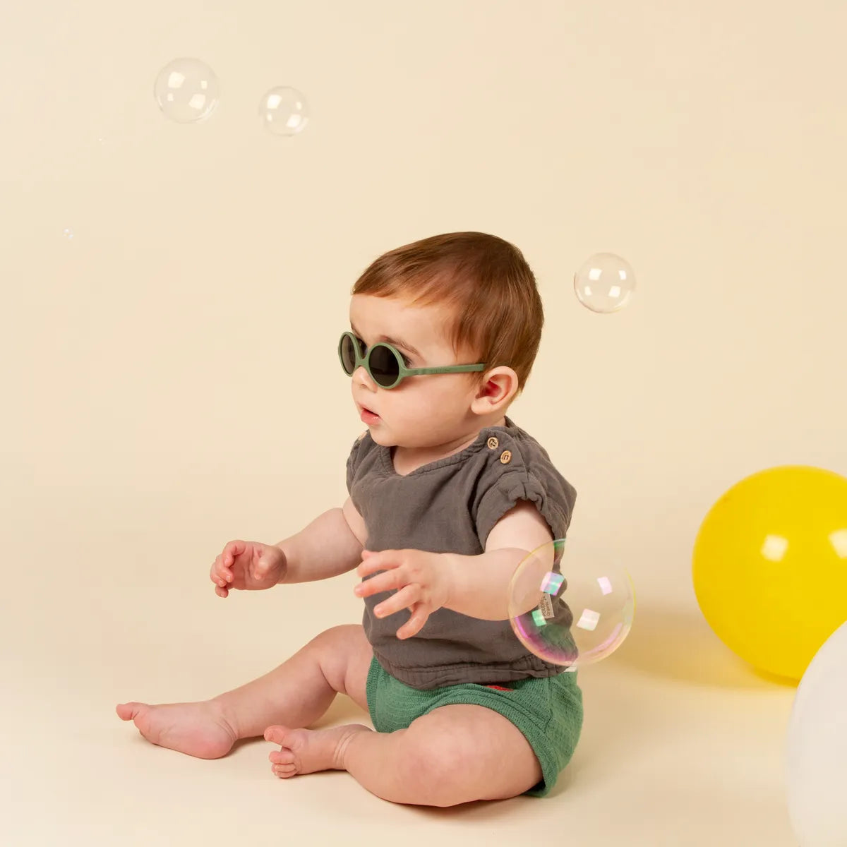 bébé assis portant lunette soleil kaki