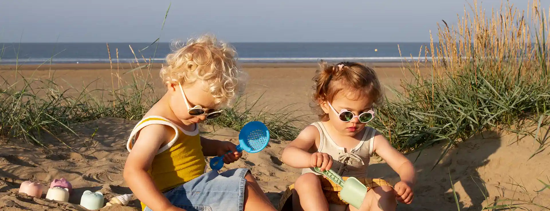  Deux enfants jouant sur la plage avec lunettes soleil