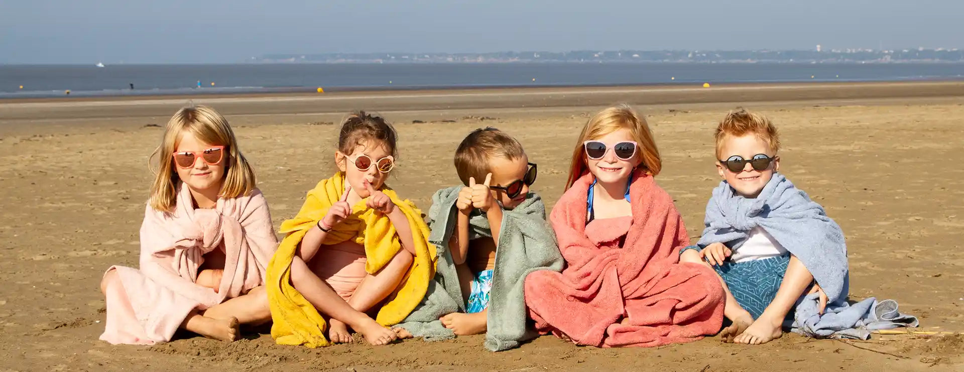 Enfants assis sur le sable avec lunette soleil